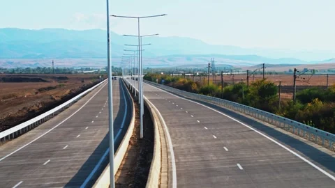 Aerial view of the highway in the rays of the setting sun and a moving cars Stock Footage 305612277