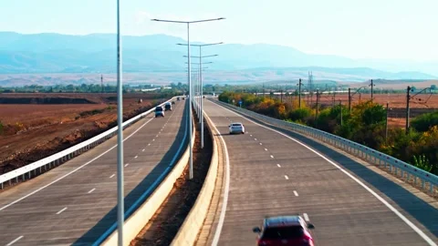 Aerial view of the highway in the rays of the setting sun and a moving cars Stock Footage 305612278