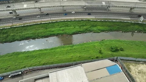 Aerial view of highway traffic alongside a green riverbank Видео 337331996
