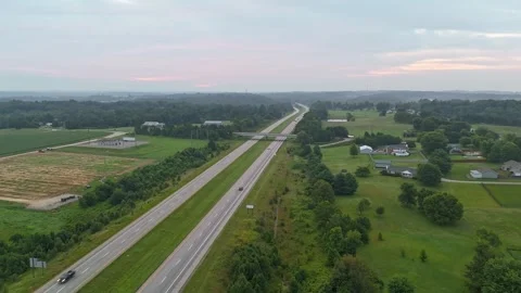 Aerial View of Highway Traffic Passing Through Rural Countryside at Sunset Vidéo 346111298