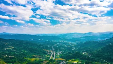 Aerial view of a highway winding through a lush green mountain valley Stock Footage 341908191