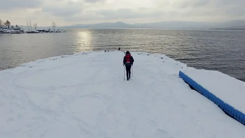 Aerial view of a hiker going alone to lake at winter Stock Footage 70569948