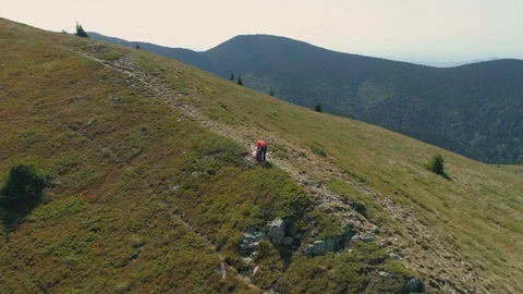 Aerial view of hiker in red jacket picking up his bag and continuing his Video stock 119326631