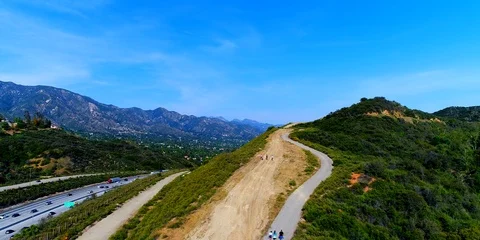 Aerial view of hikers walking alongside hills and freeway Stock Footage 99339953