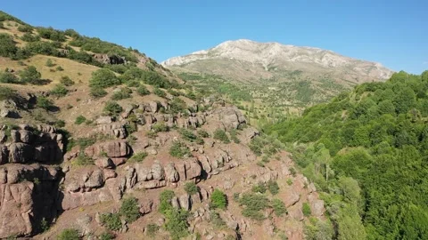 Aerial view of hill covered with trees cliffs and mountains Stock Footage 294068674