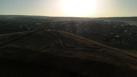 Aerial view of a hillside with a cross at the summit, overlooking a small town Vídeo Stock 332723706
