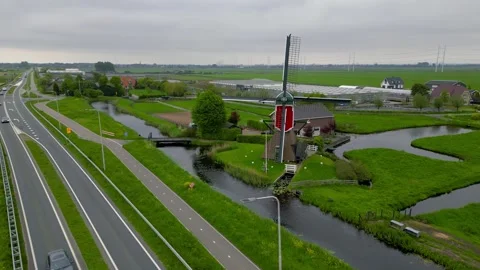 Aerial view of historic red windmill in The Netherlands between lush green .. Stock Footage 320982476