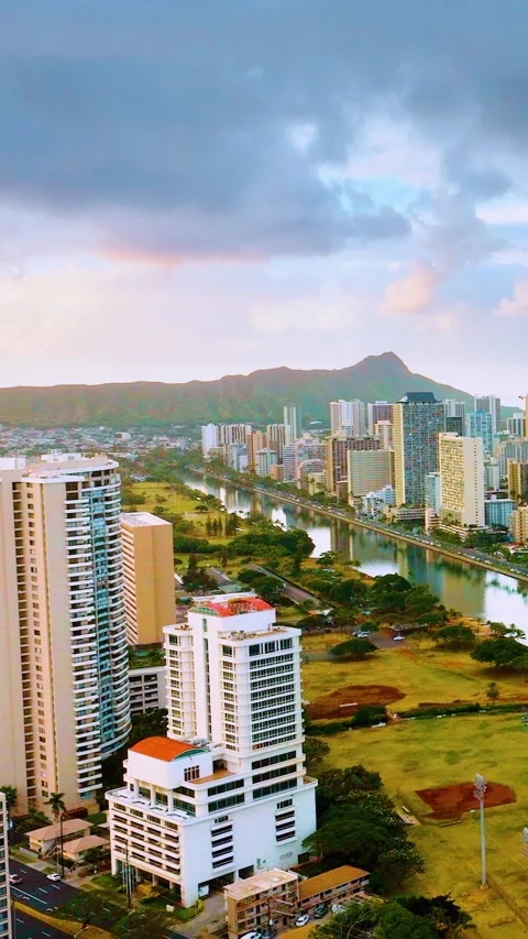 Aerial view of Honolulu with baseball fields, canal, and mountain backdrop. Video stock 319758783
