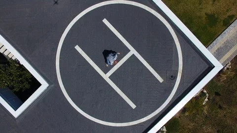 Aerial view. House with the pool. Man doing workout on helipad on roof. Capoeira Stock Footage 129559837