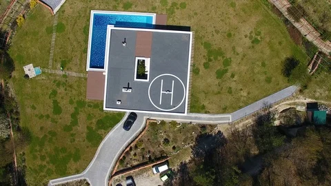 Aerial view. House with the pool. Man doing workout on helipad on roof. Capoeira Stock Footage 129559863