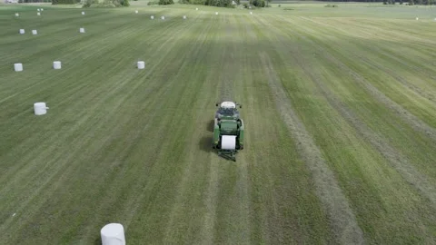 Aerial view how tractor making bales with with white film. Stock Footage 197333521