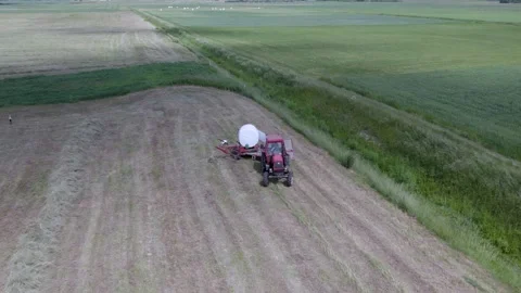 Aerial view how tractor making bales with with white film. Stock Footage 198799272