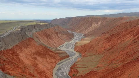 Aerial view of huge red canyon, winding muddy river, cliff road in Xinjiang Stock Footage 345522249