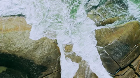 Aerial view of huge waves hitting stones with white foam Stock Footage 331762870