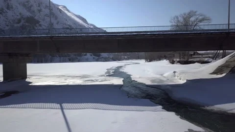Aerial view of an icebound river. Bridge over mountain river. Winter sunny day. Stock Footage 140321304