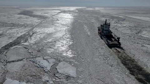 Aerial view of an icebreaker ship navigating through frozen sea ice Stock Footage 335352548