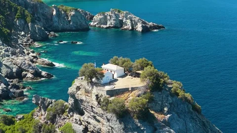 Aerial view of the iconic Agios Ioannis Church perched dramatically atop a rocky Stock Footage 346704663