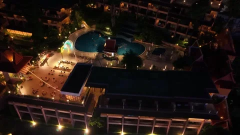 Aerial view of illuminated hotel pool area with lounge chairs at night Video stock 342331857
