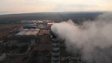 Aerial view of an industrial pipe polluting the air next to living people. 4K. Stock Footage 87553407
