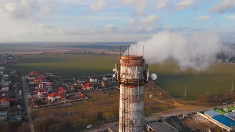 Aerial view of an industrial pipe polluting the air next to living people. 4K. Stock Footage 87555403