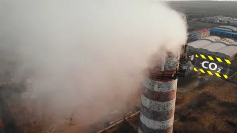 Aerial view of an industrial pipe polluting the air next to living people. 4K. Stock Footage 87573138
