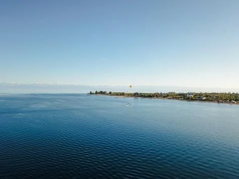Aerial view of Issyk-Kul lake beach with tourist and parachuting person Stock Photos