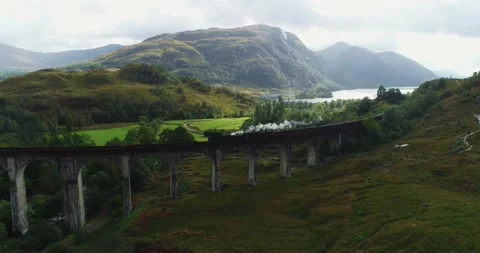 Aerial view of the Jacobite Steam Train crossing Glenfinnan Viaduct in Scotland Stock Footage 159672365