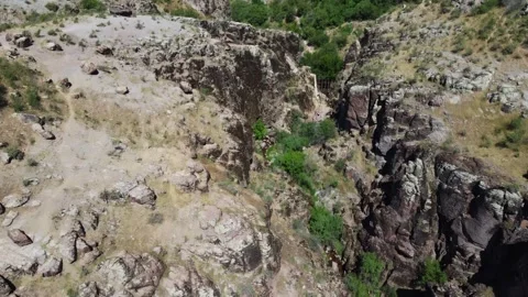 Aerial view of jagged basalt canyon with green bush clusters in Kazakhstan Видео 337667293