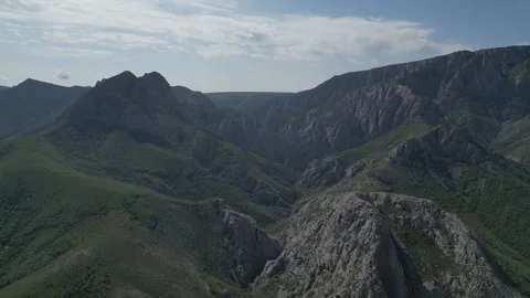 Aerial view of jagged, dark mountain peaks and ridges under a cloudy sky. Stock Footage 334671988