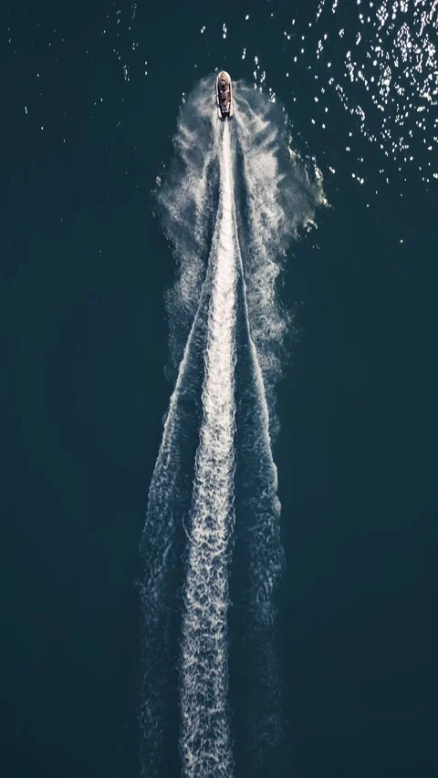 Aerial view of a jet ski speeding across dark blue water, leaving a dynamic Stock Footage 310803256
