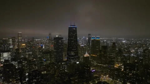 Aerial view of the John Hancock tower, hazy night in Chicago, USA - pull Stock Footage 233559860
