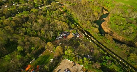 Aerial view of junk yard in with stacks of used cars in wooded area in Stockbeeldmateriaal 239036751