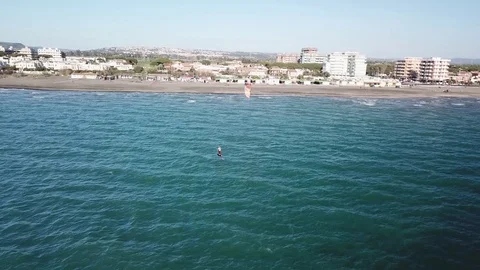 Aerial view of A Kite surfer sails in front of a sand beach in a sunny windy day Stock Footage 106531718