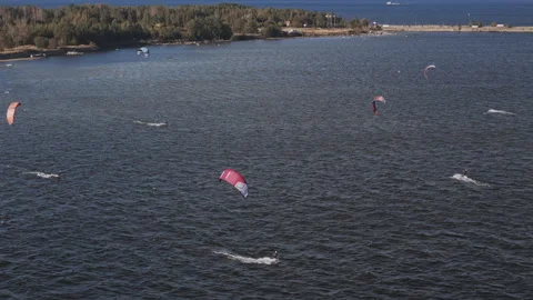 Aerial view of kite surfers gliding over water with colorful kites in motion Stock Footage 345538465