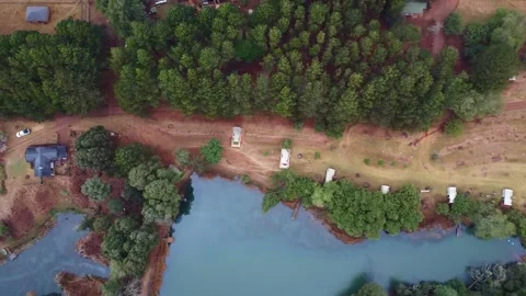 Aerial view of a lake surrounded by trees and a road with vehicles parked along Stock Footage 308979230