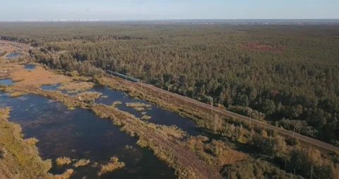 Aerial view of lakes, fields, forest and railway with moving train Stock Footage 345370634