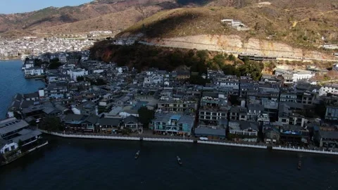 Aerial view of lakeside connected Bai residence at mountain foot lake bay in Stock Footage 337923564