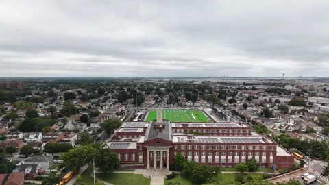 Aerial view of a large brick campus with solar panels and athletic field in Stock Footage 345422963