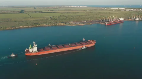 Aerial view of a large cargo ship leaving the harbor with tugboats at sunset. 스톡 동영상 157684831