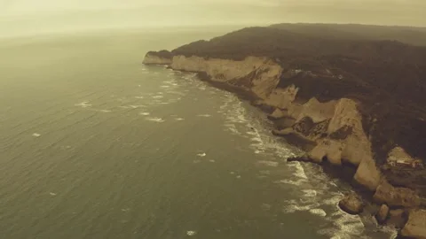Aerial view of large cliffs along the ocean with a warm filter Stock Footage 146754625