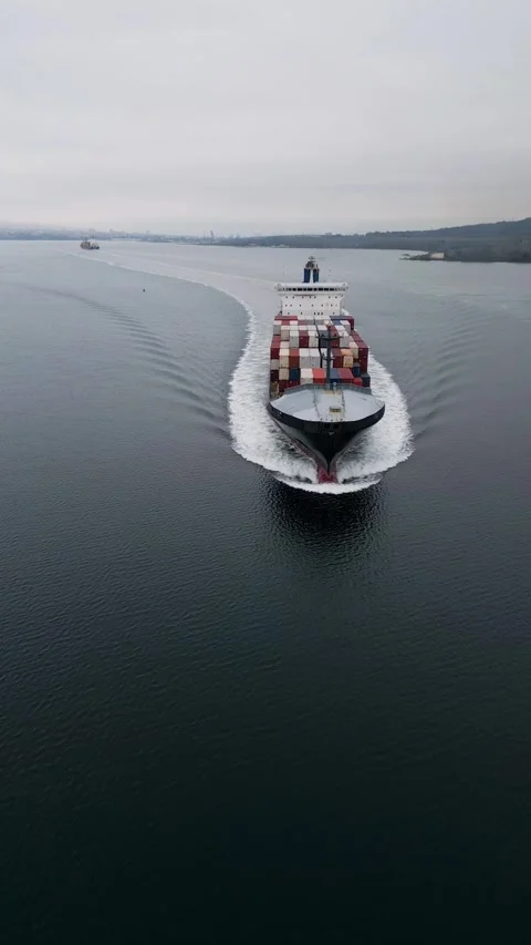 Aerial view of large container ship moving across calm sea, leaving wake behind Video stock 324855679
