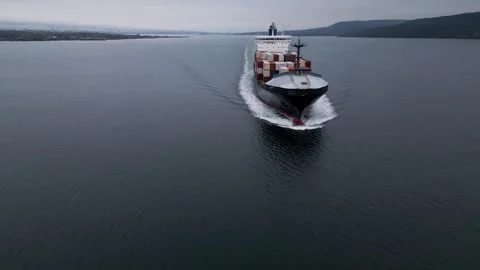 Aerial view of large container ship moving across calm sea, leaving wake behind. 库存影片 325741251