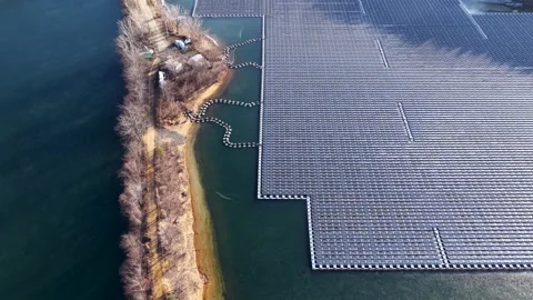 Aerial view of large floating solar panel array with its shore attachment Stock Footage 327371579