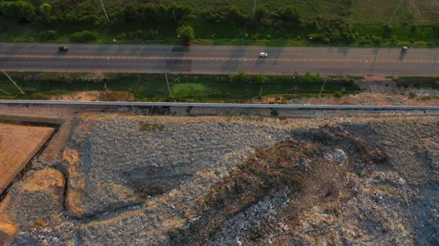 Aerial view, large garbage pile at sorting site with roadway. Camera is truck Stock Footage 141586171
