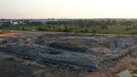 Aerial view, large garbage pile at sorting site with industrial factory. Panning Stock Footage 141588043
