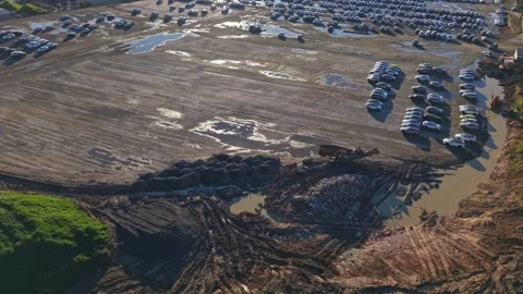 Aerial view of a large new car lot in a muddy industrial area Stock Footage 340123501