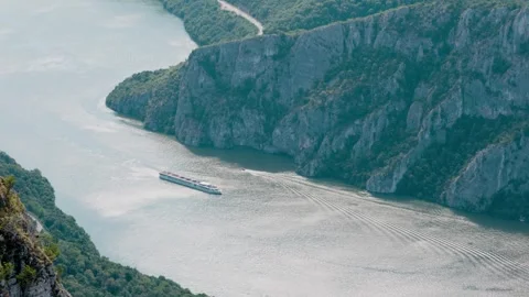 Aerial view of a large passenger river cruise ship sailing through a narrow Stock Footage 344728929