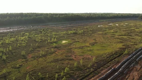 Aerial view of a large peat bog harvesting site with long parallel rows of Stock Footage 315734084