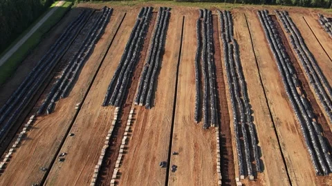 Aerial view of a large peat bog harvesting site with long parallel rows of Stock Footage 315734345