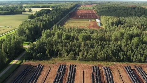 Aerial view of a large peat bog harvesting site with long parallel rows of Stock Footage 315742328